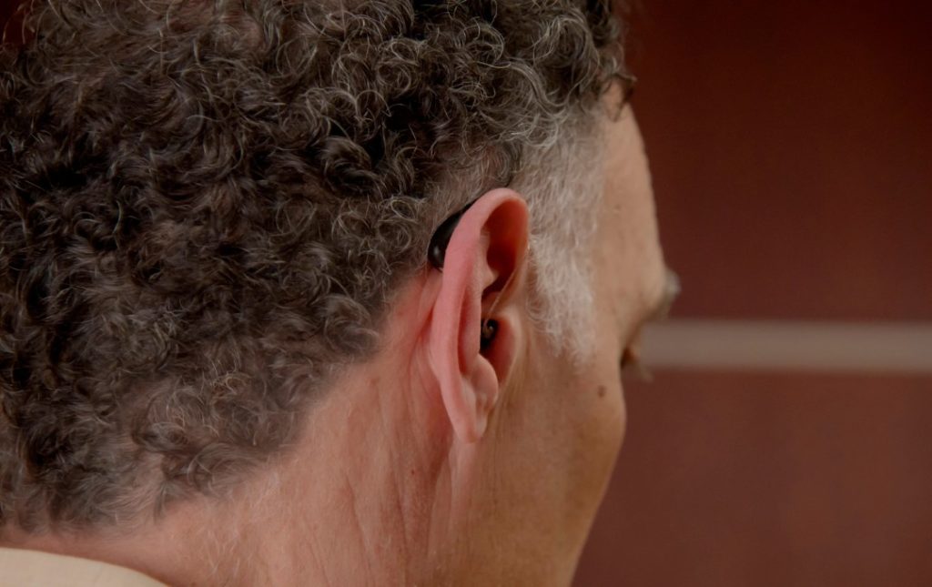 hombre usando audifonos recargables para sordos tipo RIC discretos para perdida auditiva